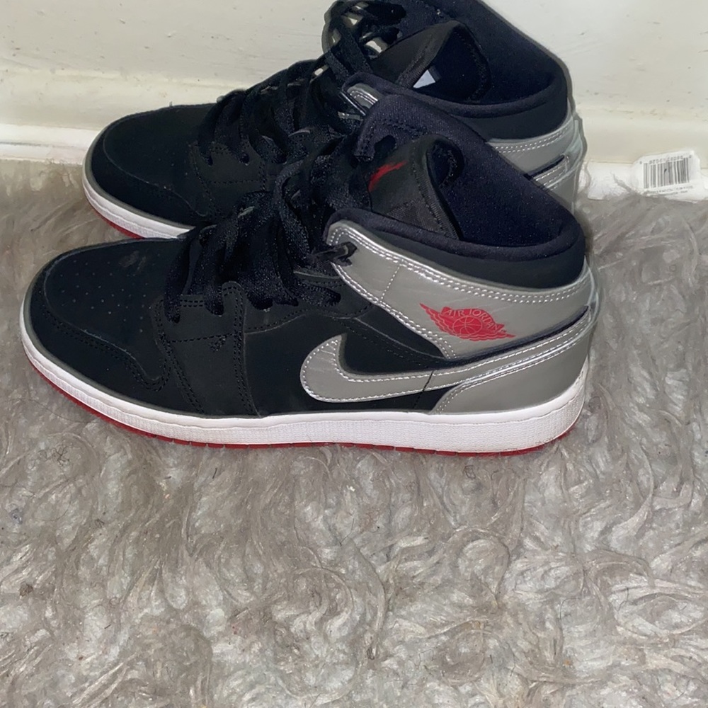 Jordan 1s retro black and silver with red on the bottom .